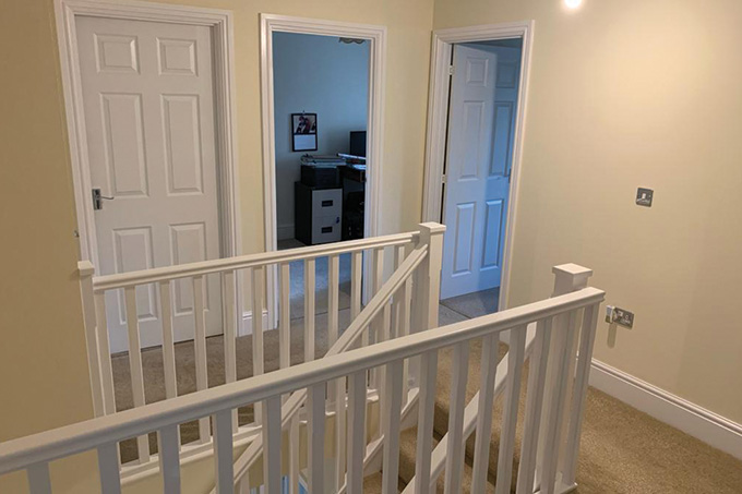 the landing of the staircase with painted walls, bannister and door frames